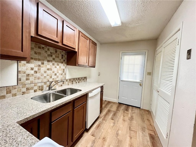 kitchen with dishwasher, sink, light stone countertops, and light wood-type flooring