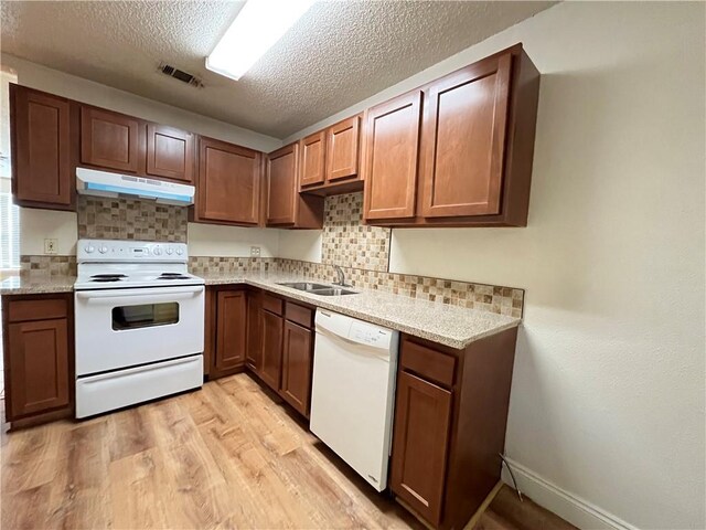 kitchen with decorative backsplash, white appliances, sink, and light hardwood / wood-style flooring