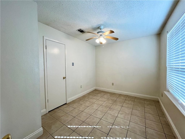 tiled spare room with ceiling fan and a textured ceiling