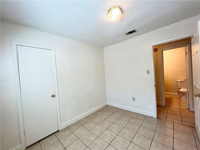 unfurnished room with light tile patterned floors and a textured ceiling