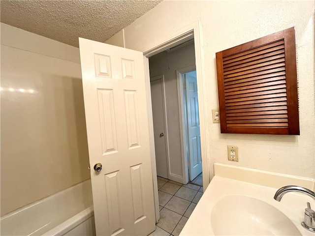 bathroom with a textured ceiling, sink, and tile patterned floors