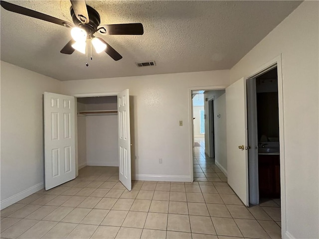 unfurnished bedroom featuring light tile patterned floors, a textured ceiling, a closet, and ceiling fan