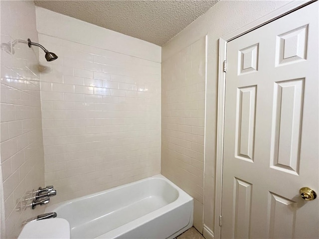 bathroom with a textured ceiling and tiled shower / bath