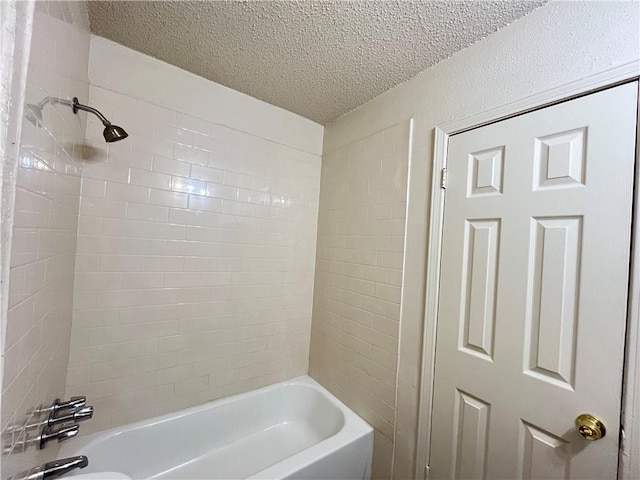 bathroom with a textured ceiling and tiled shower / bath combo