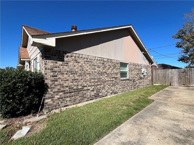 view of side of home featuring a lawn and a patio