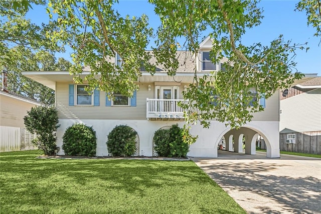 view of front facade with a balcony, a front lawn, and a carport