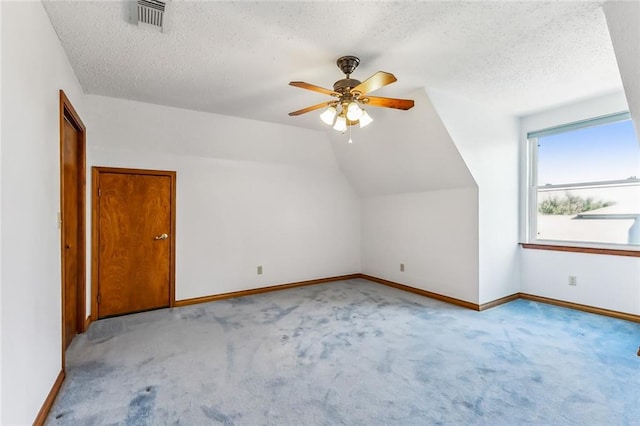 additional living space featuring lofted ceiling, ceiling fan, light carpet, and a textured ceiling