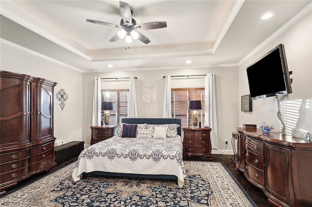 bedroom featuring ceiling fan, dark hardwood / wood-style flooring, ornamental molding, and a tray ceiling