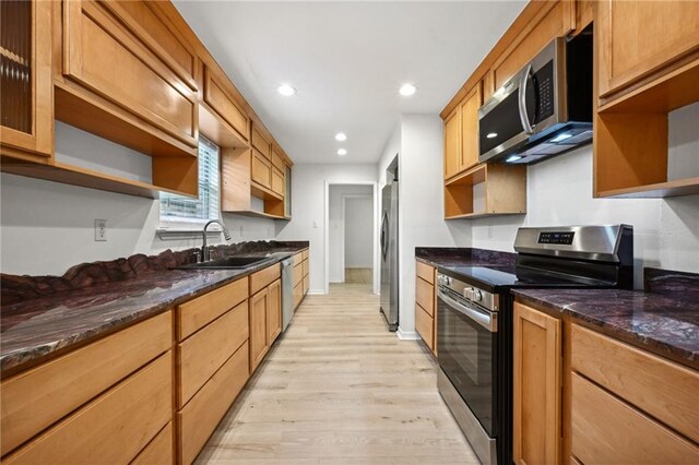 kitchen featuring sink, appliances with stainless steel finishes, light wood-type flooring, and dark stone countertops