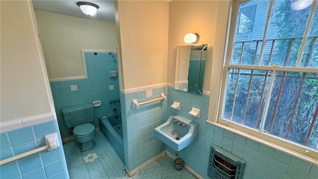 full bathroom featuring tile patterned flooring, heating unit, toilet, and tile walls