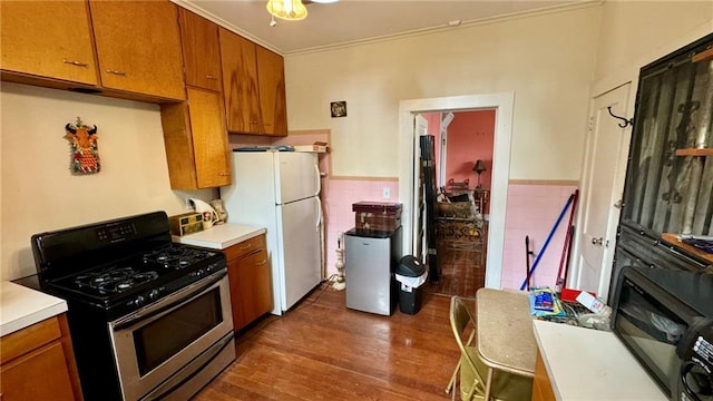 kitchen featuring ornamental molding, dark wood-type flooring, stainless steel range oven, and white refrigerator