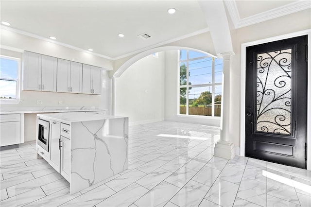 interior space with decorative columns, plenty of natural light, and ornamental molding