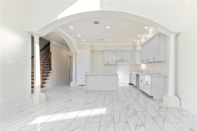 kitchen with stainless steel dishwasher, a kitchen island, ornamental molding, and sink