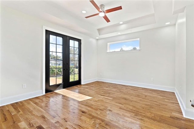 spare room featuring a tray ceiling, ceiling fan, french doors, and wood-type flooring