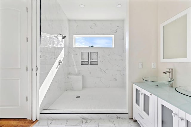 bathroom with a tile shower and vanity