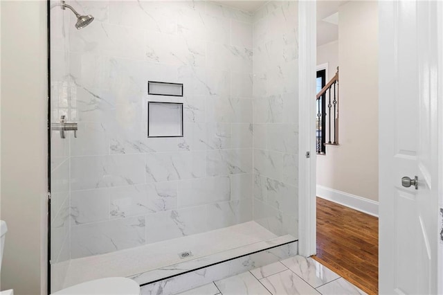 bathroom with tiled shower, toilet, and hardwood / wood-style flooring