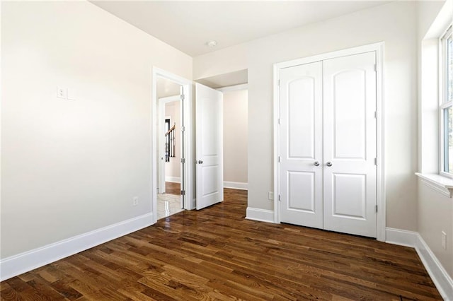 unfurnished bedroom with dark hardwood / wood-style floors and a closet