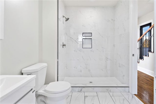 bathroom featuring hardwood / wood-style floors, vanity, toilet, and tiled shower