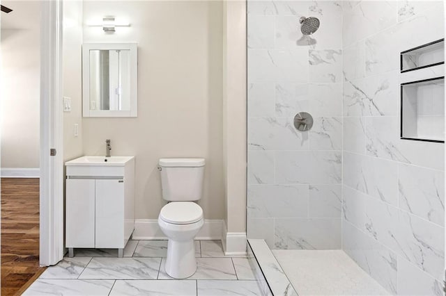 bathroom featuring tiled shower, hardwood / wood-style floors, vanity, and toilet