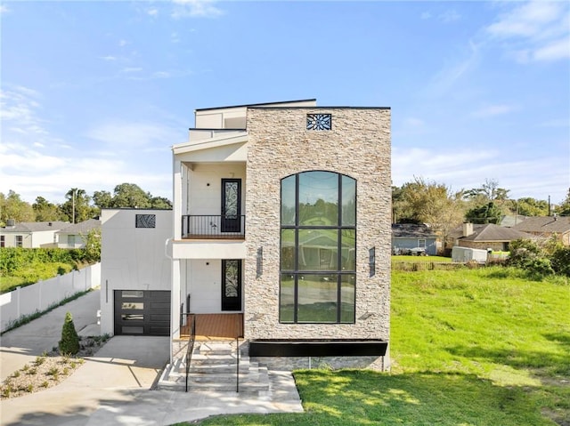 contemporary home with a balcony, a front yard, and a garage