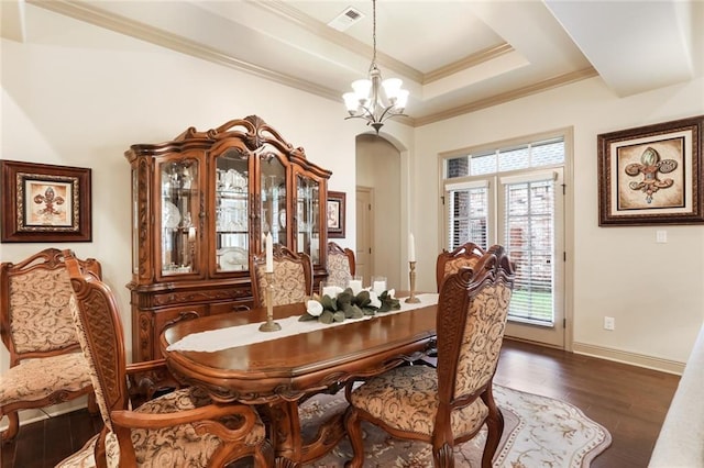 dining space featuring a notable chandelier, a raised ceiling, ornamental molding, and dark wood-type flooring