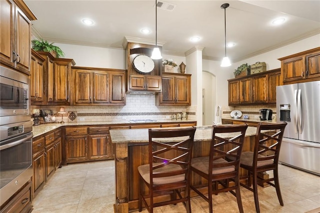 kitchen with a kitchen breakfast bar, light stone counters, stainless steel appliances, decorative light fixtures, and a center island