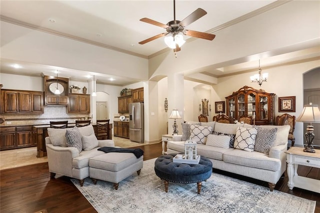 living room featuring wood-type flooring, ceiling fan with notable chandelier, and ornamental molding