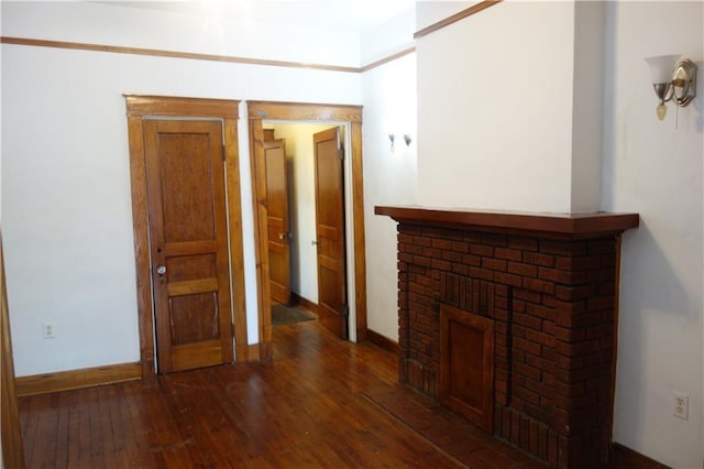 unfurnished living room with dark hardwood / wood-style floors and a brick fireplace