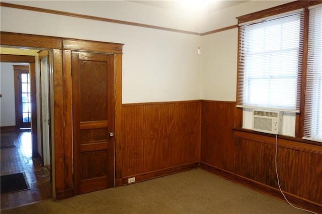 carpeted spare room featuring plenty of natural light, cooling unit, and wood walls