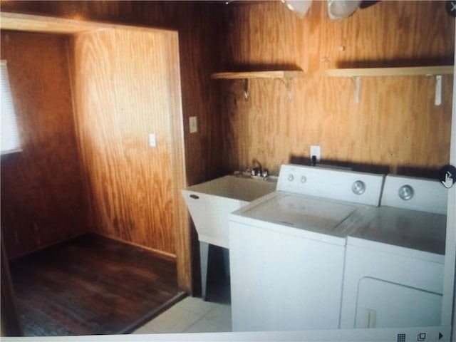 laundry room featuring washer and dryer, light hardwood / wood-style flooring, and wooden walls