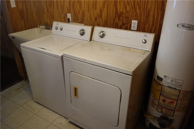 washroom featuring wood walls, water heater, light tile patterned floors, and independent washer and dryer