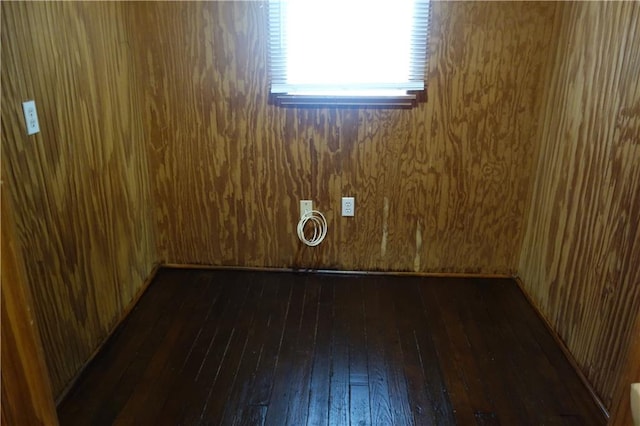 unfurnished room with dark hardwood / wood-style flooring and wooden walls