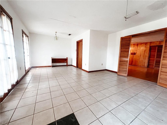 tiled empty room with a chandelier and wooden walls