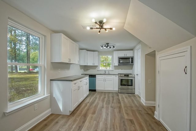 kitchen featuring light wood-type flooring, stainless steel appliances, sink, a chandelier, and white cabinetry