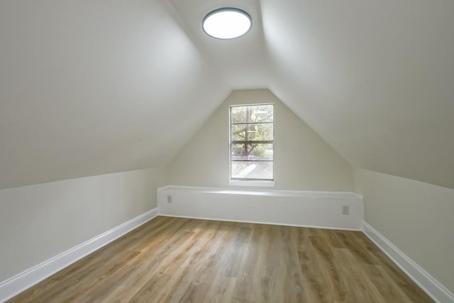 additional living space with light wood-type flooring and vaulted ceiling