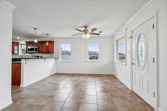 interior space featuring ceiling fan, a kitchen breakfast bar, kitchen peninsula, decorative light fixtures, and ornamental molding