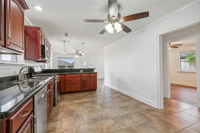 kitchen with dark stone counters, stainless steel appliances, crown molding, sink, and decorative light fixtures