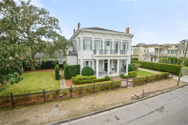 italianate home featuring a balcony, covered porch, and a front lawn