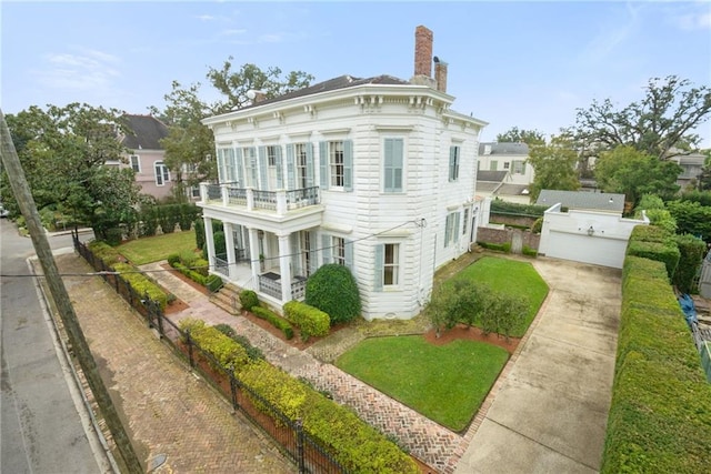 view of front of home featuring a balcony, a garage, a chimney, and a front yard