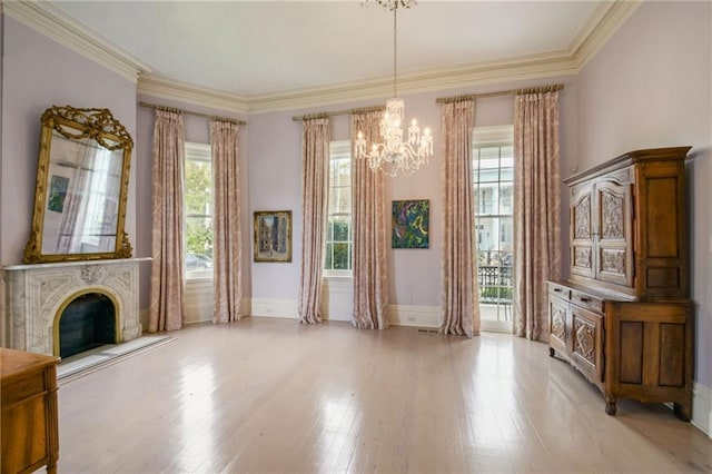 interior space featuring light wood-type flooring, crown molding, a chandelier, and a healthy amount of sunlight