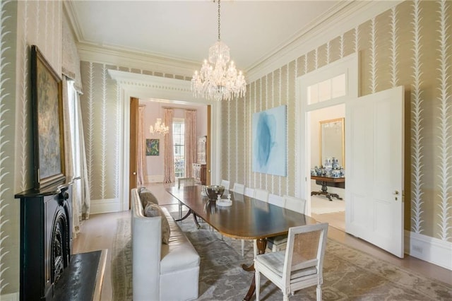 dining space featuring ornamental molding, wood finished floors, an inviting chandelier, and wallpapered walls