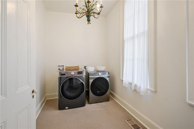 washroom featuring washer and dryer, plenty of natural light, carpet floors, and a chandelier