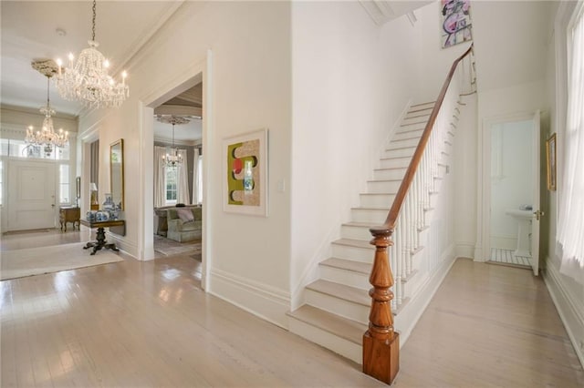 staircase with hardwood / wood-style floors, a chandelier, and ornamental molding