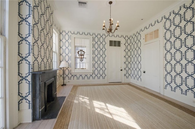 unfurnished living room featuring an inviting chandelier, light wood-type flooring, and ornamental molding