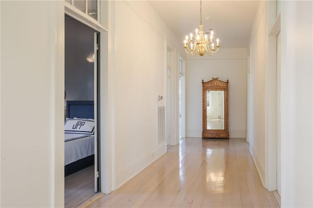 hall featuring light wood-type flooring and a chandelier