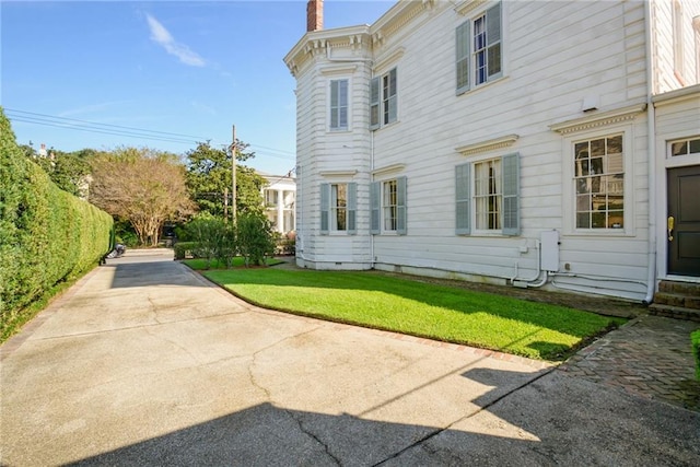 view of side of property featuring a yard and a chimney