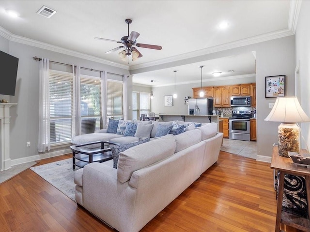 living room with ceiling fan, light wood-type flooring, and ornamental molding