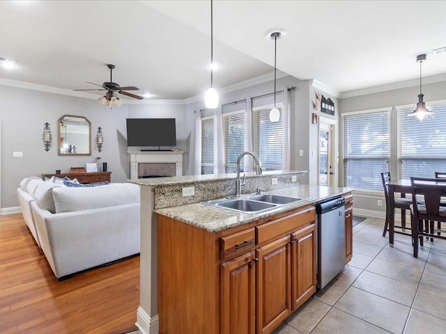 kitchen featuring dishwasher, sink, pendant lighting, a center island with sink, and light wood-type flooring