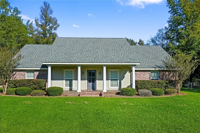 view of front of house with stucco siding, a shingled roof, a front lawn, and brick siding