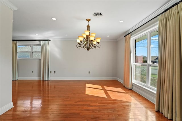 spare room featuring an inviting chandelier, light hardwood / wood-style flooring, and crown molding